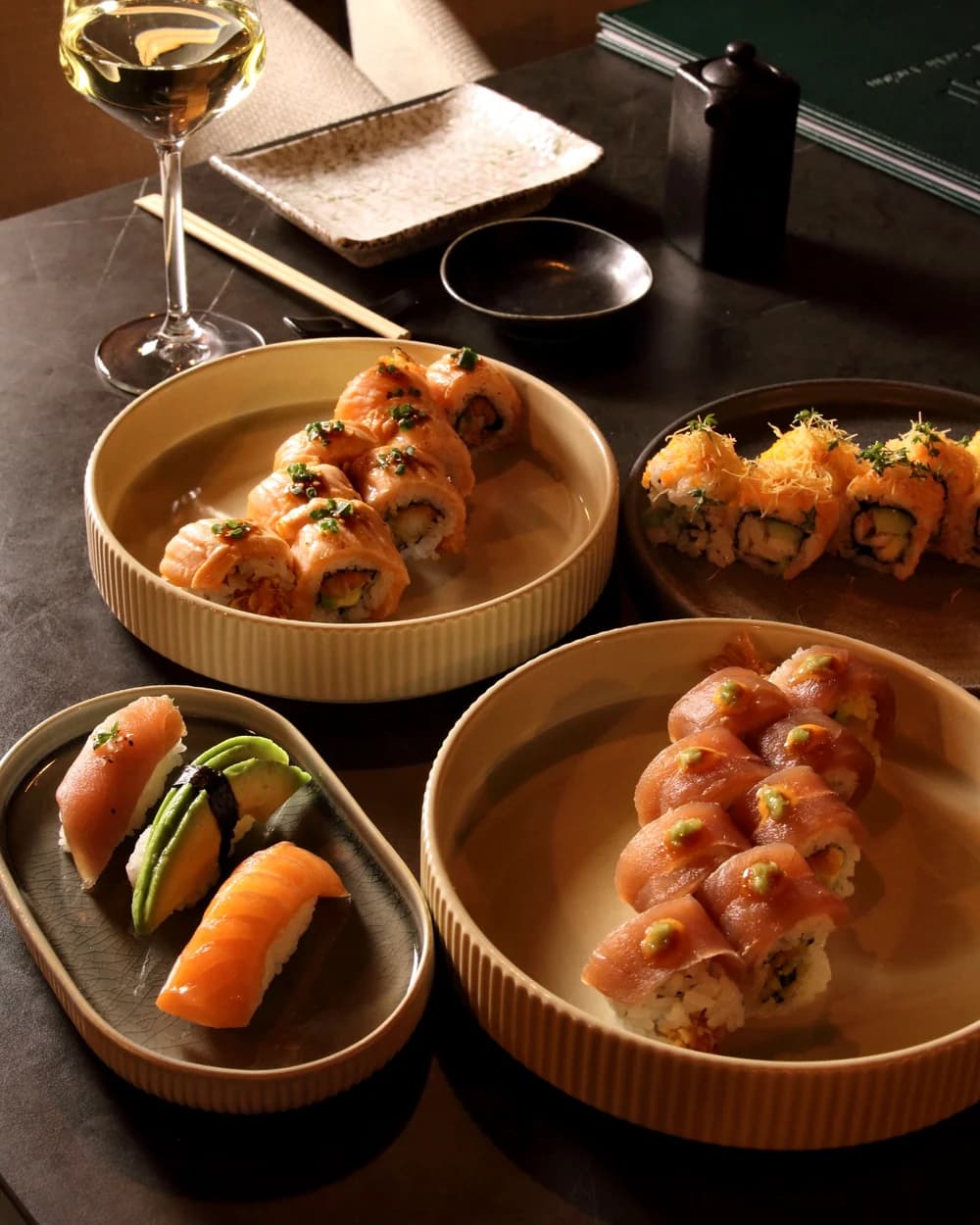 Sushi rolls and nigiri on several plates on a set table